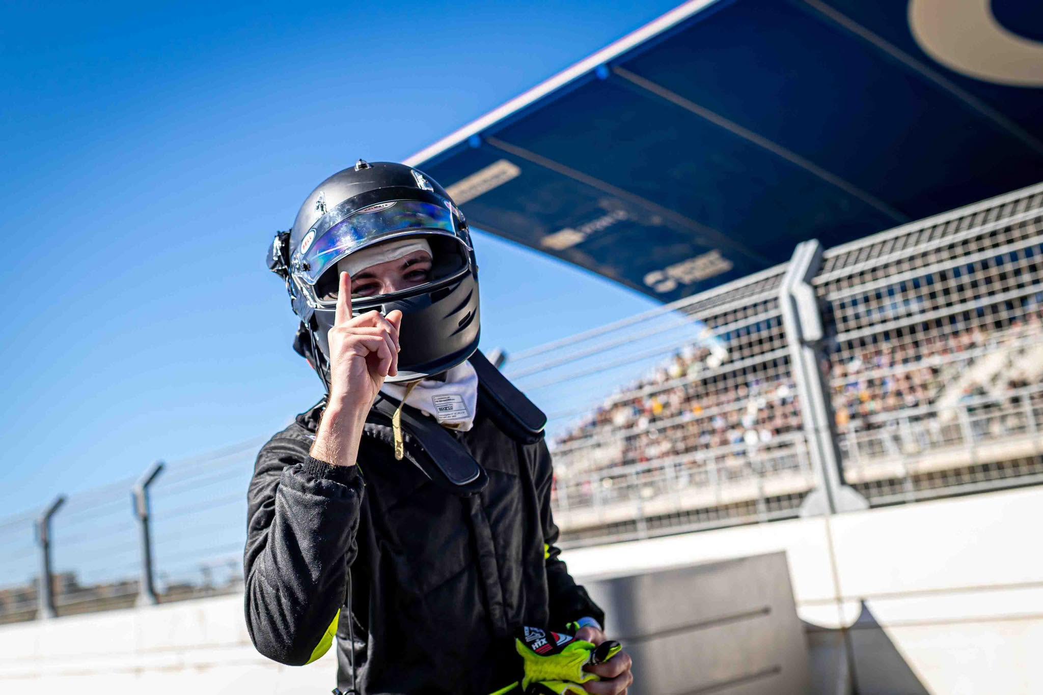 A driver celebrating a race win, pointing to the sky