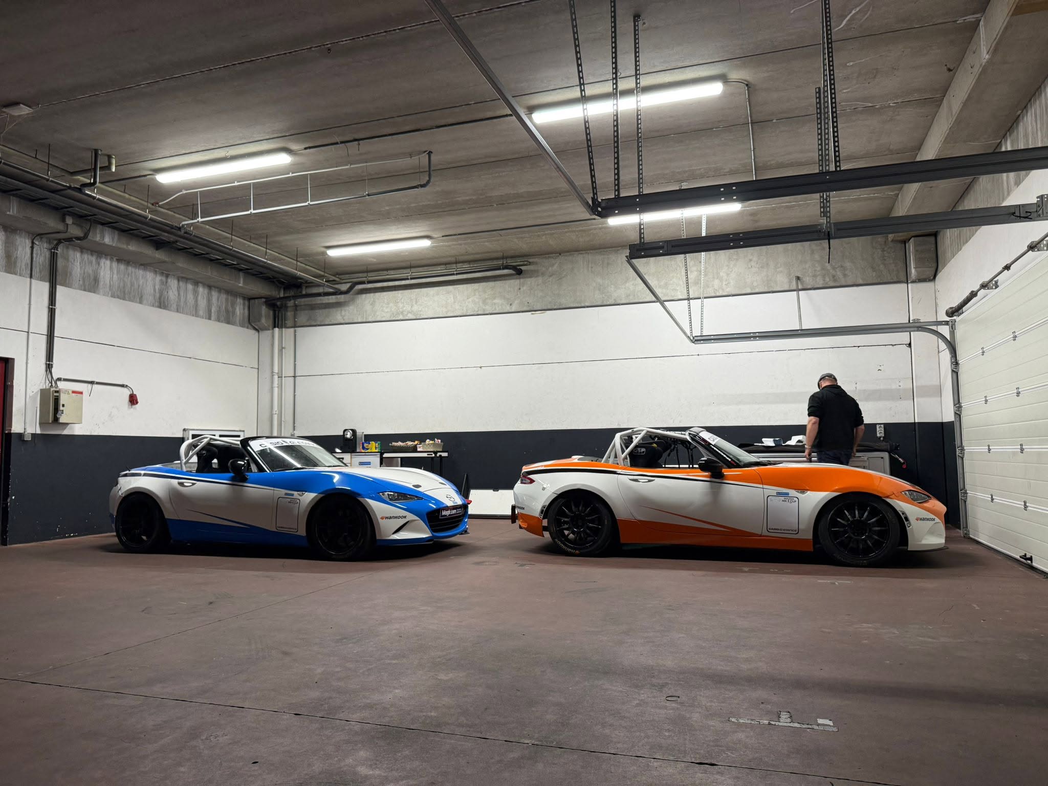 Two NiceRacing Mazda MX-5 Cup cars side by side in the EJ Automotive workshop